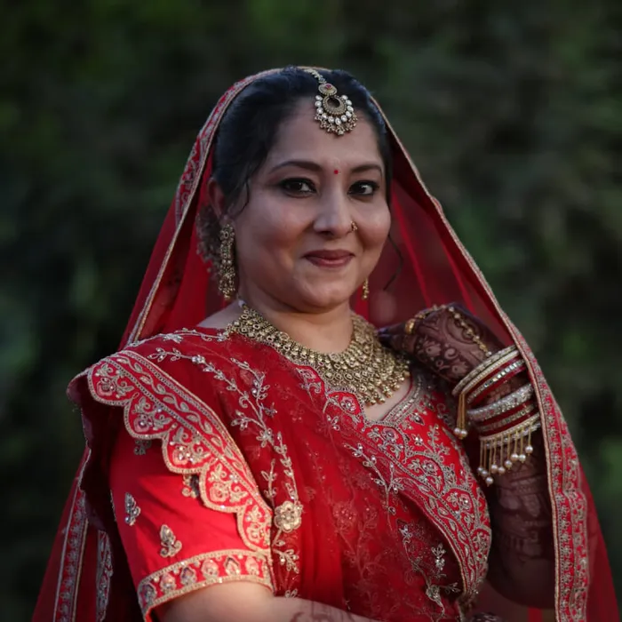 Bridal makeover in red lehenga with traditional gold jewelry at Megha Makeover & Beauty Salon, Ahmedabad